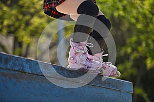 Skater girl grinding on a ledge in a outdoor skatepark in summer. Aggressive inline roller blader female performing a bs royale