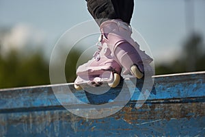 Skater girl grinding on a ledge in a skatepark. Female inline roller blader performing grind trick