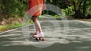 skater girl is riding on skateboard at summer vacation in forest park