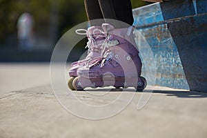 Skater girl wearing modern aggressive in-line skates in a skatepark. Young female skating on roller blades in summer