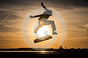 Skater make trick kickflip against the beautiful orange sunset photo
