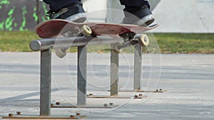 Skater make grind trick feeble on rail in skatepark, close-up view in slowmotion