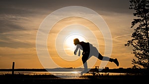 Skater on road make wide pushing against the sunset