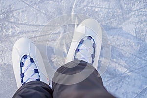 Skater`s legs standing on winter ice rink.Woman skating and training with white skates on the ice area in winter day