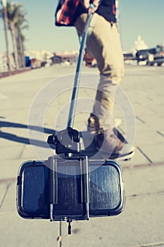 Skater taking a self-portrait or a video with a selfie stick