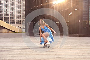 Skater woman in dress is training on longboard, doing a trick outdoor in a public park, sunrise in the morning industrial city vie