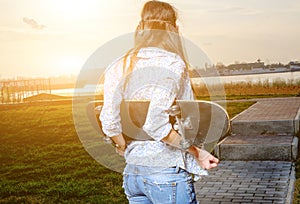 Skater young woman on sunset. Woman with