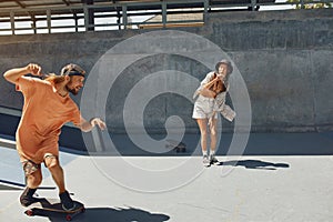 Skaters. Girl And Guy At Skatepark. Portrait Of Hipster Friends In Casual Outfit Riding On Skateboard Outdoors