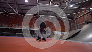 Skaters, rollers and people on a bike rest together in a skate park. slow motion