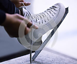 Skates over stilletos anyday. an unrecognisable figure skater tying the laces on her ice skates.