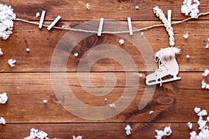 Skating on winter concept, white ice skate hanging on wooden brown background with snowflakes, top view with copy space