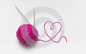 Skein of wool pink with spokes and thread in the shape of a heart on a white background