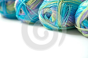 Skeins of multi-colored gradient yarn for knitting children`s clothes on white background. Gentle multicolor yarn of blue, green,