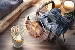 Skeins of yarn for knitting, knitting and knitting needles in wicker basket in rustic interior. Knitting or relaxation