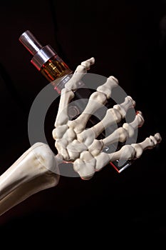 Skeleton hand holding an ecigarette with ejuice in it
