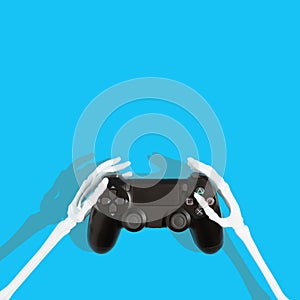 Skeleton hands holding black video game controller. Light blue background. Copy space. Minimal gaming concept