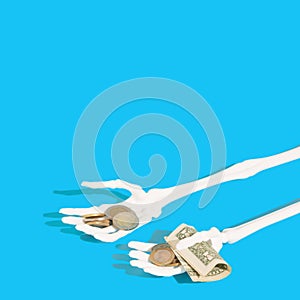 Skeleton hands holding money. Light blue background. Copy space