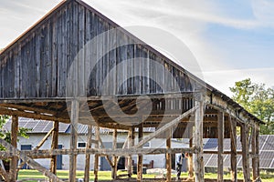 The skeleton of an old, destroyed barn being demolished on a sunny day. Grass