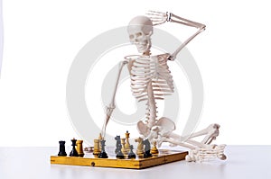 Skeleton playing chess game on white