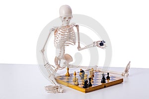 The skeleton playing chess game on white