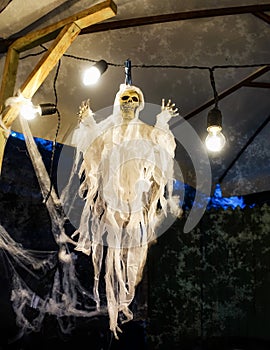 A skeleton in a shroud and cobwebs hangs photo