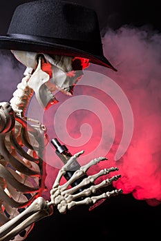 Skeleton wearing a hat vaping clouds of red highlighted vapor with an ecigarette