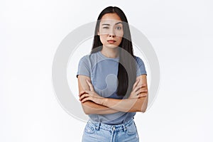 Skeptical and doubting young asian woman cross hands over chest in bossy, professional pose, stare judgemental and photo