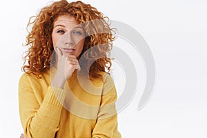 Skeptical, judgemental redhead woman with curly hair, rub chin and squinting as looking camera, give-out her opinion photo