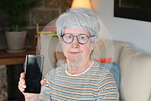 Skeptical senior woman showing smartphone