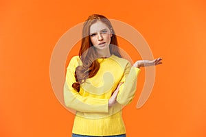 Skeptical and troubled, uncertain young redhead woman cant understand how resolve proble, shrugging raise hands sideways