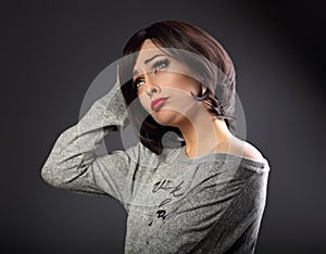 Skeptical unhappy grimacing thinking young woman with short black hair style looking up on empty copy space grey background