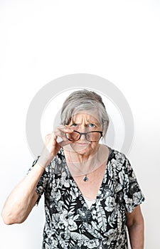 Skeptical woman looking at camera while peering over her eye glasses. White isolated background