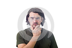 Skeptical young man thoughtful looking to camera, keeps hand under chin, puzzled suspicious expression isolated on white