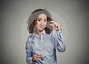 Skeptical young woman showing small amount gesture with hand fingers