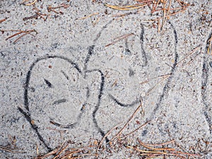 Sketch of two funny and laughing faces painted in the sand on a footpath