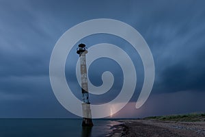 Skew lighthouse in the Baltic Sea. Stormy night and lightning.