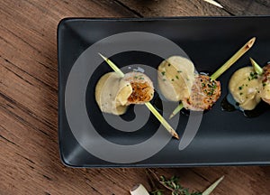 A skewer of seared hokkaido scallops with lemongrass flavouring served with curry cauliflower sauce