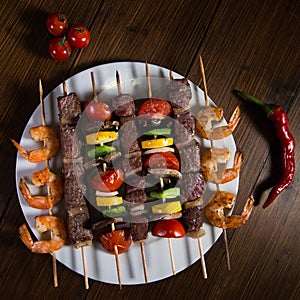 Skewered meat, shrimp and vegetables on a plate