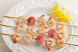 Skewered shrimp with cherry tomatoes on wooden skewers and lemon