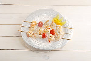 Skewered shrimp with cherry tomatoes on wooden skewers and lemon