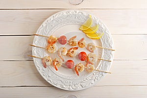 Skewered shrimp with cherry tomatoes on wooden skewers and lemon