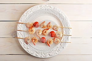 Skewered shrimp with cherry tomatoes on wooden sticks