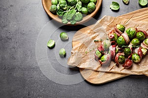 Skewers with Brussels sprouts and bacon served on table, flat lay. Space for text
