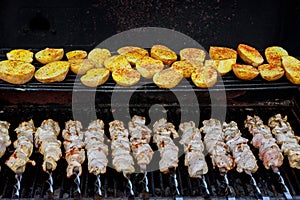 Skewers made from potatoes and meat as well as kebabs on the grill outdoors