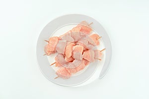 Skewers from raw chicken meat fillet on a white plate for supermarket on white background.Food for retail.Raw Chicken