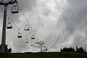 Ski chair lift going up a mountain on an overcast day