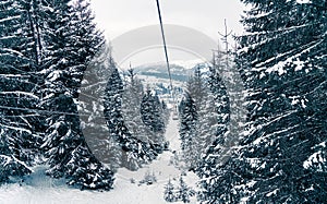 Ski elevator or funicular in snowy forest landscape winter. Panoramic view of frozen mountains background with fir trees covered