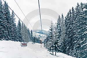 Ski elevator or funicular in snowy forest landscape winter. Panoramic view of frozen mountains background with fir trees covered
