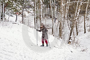 Ski girl climbing uphill in winter forest