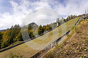 Ski jump hill in front of a mountain and green autumn fall forest in Julijske Alpe Alpi Giulie Alps, Slovenia Slovenija